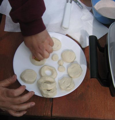 Kids enjoy helping with campout cooking, such as cutting the holes out of doughnut dough.