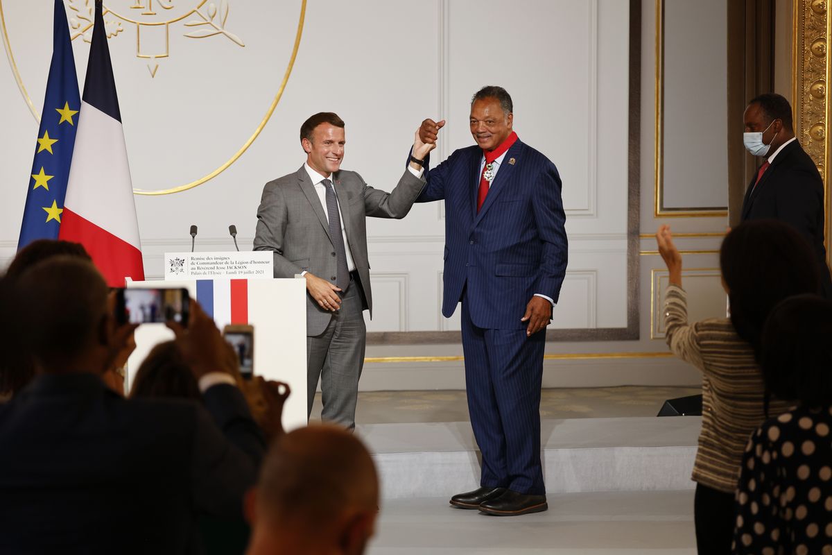 French President Emmanuel Macron, left, and Reverend Jesse Jackson raise their hands after Jackson was awarded with the Legion d