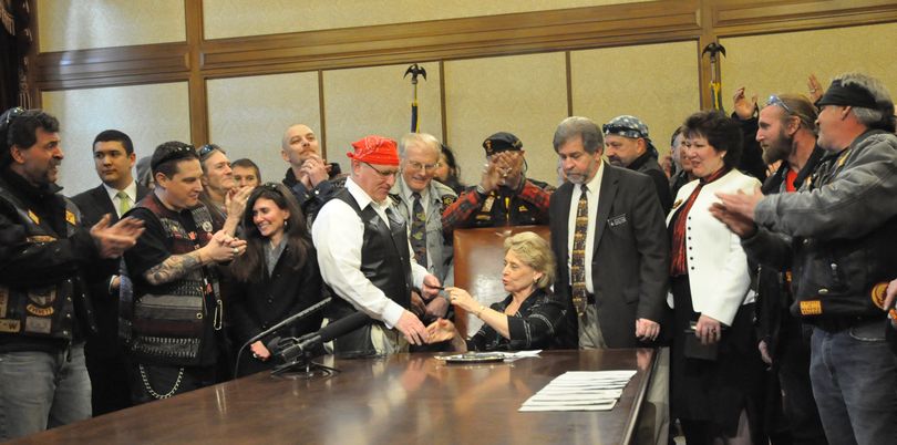 Gov. Chris Gregoire hands Sen. Jim Hargrove a pen after signing a bill to outlaw 