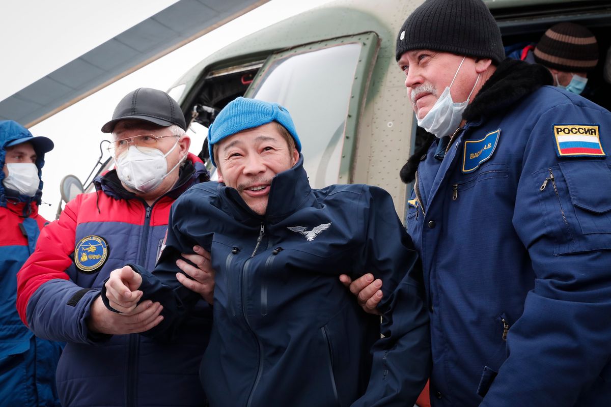 Space flight participant Japanese entrepreneur Yusaku Maezawa is assisted as he disembarks from a helicopter as he arrives at the airport after returning from the International Space Station on the Soyuz MS-20 space capsule, in Zhezkazgan, Kazakhstan, Monday, Dec. 20, 2021. A Japanese billionaire, his producer and a Russian cosmonaut safely returned to Earth on Monday after spending 12 days on the International Space Station.  (Shamil Zhumatov)