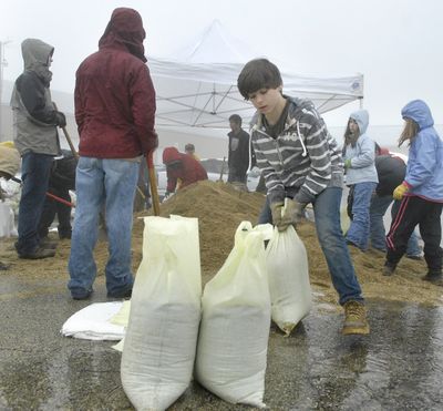 Adam Koehl, 11,  moves a sandbag while he and other Boy Scouts help fill some 2,400 sandbags in Lily Lake, Ill., on Saturday.  (Associated Press / The Spokesman-Review)