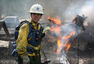 
Firefighter Kevin Ward  waits for water to extinguish a flare-up of  a brush fire on Saturday on the Chehalis Indian Reservation. The 2-acre fire, which also destroyed a shed and the neighborhood pumphouse, is believed to have been started by fireworks.
 (Associated Press / The Spokesman-Review)
