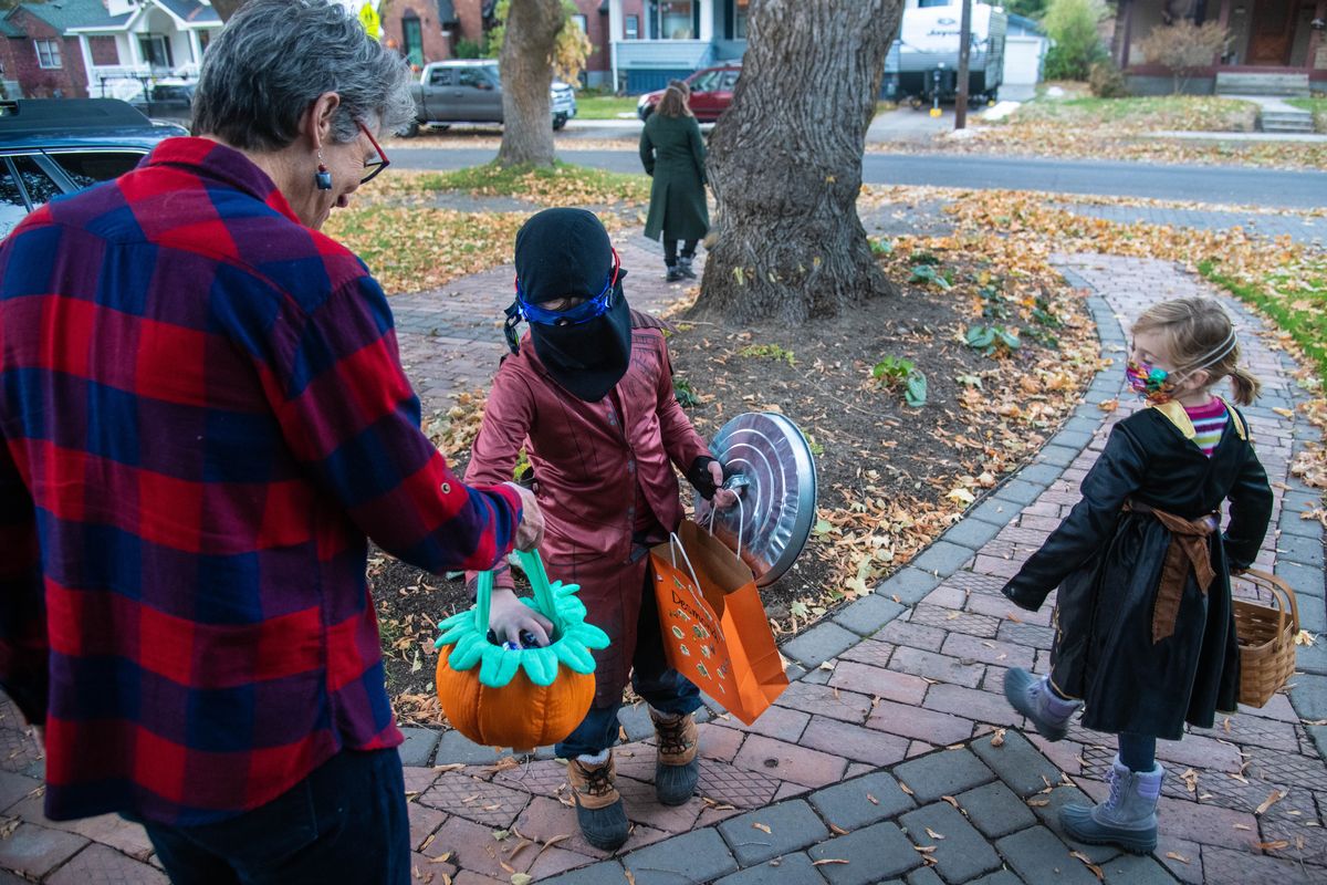 Carolyn Ringo offers up and candy treats to Desmond Truitt, 9, and his sister, Madeline, 7, Saturday during Halloween activities along 17th Avenue in Spokane.  (DAN PELLE/THE SPOKESMAN-REVIEW)