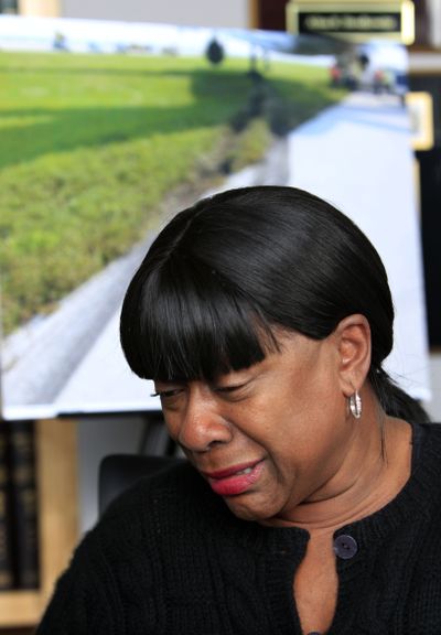 Jewel Thomas sits in front of a photo of skids marks leading to the plane she was on that ran off a runway two years ago.  (Associated Press)