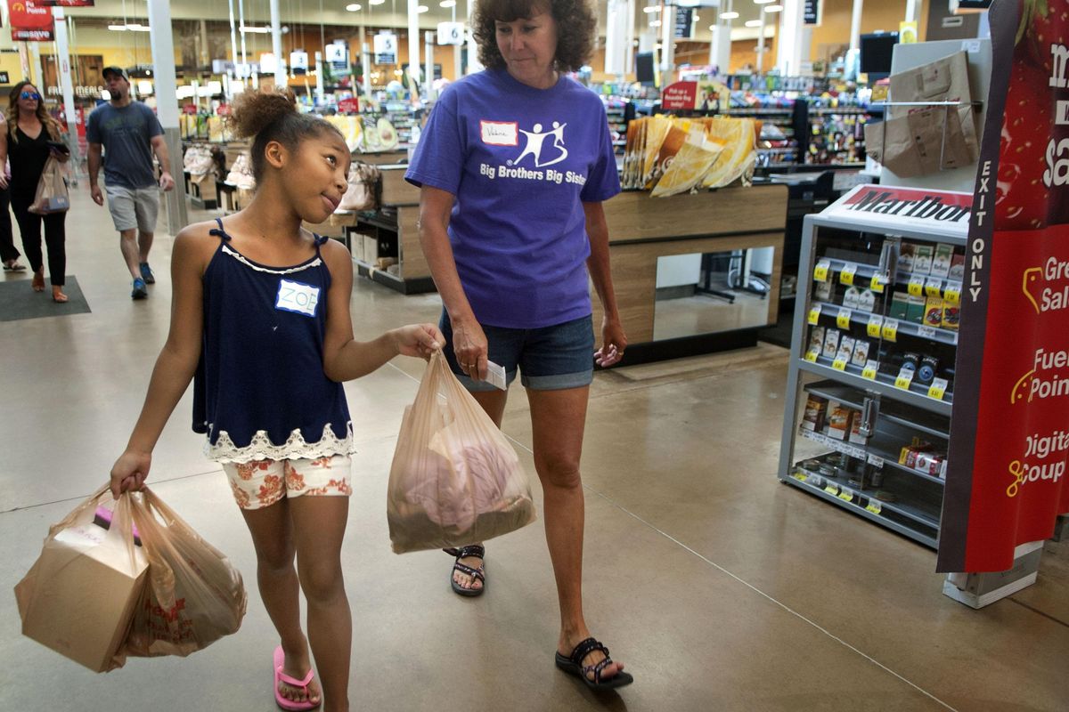 Nine-year-old Zoe Fletcher Francis walks with Big Brothers Big Sisters volunteer Valerie Shelton after a free shopping trip at Fred Meyer on Saturday, August 3, 2019. (Kathy Plonka / The Spokesman-Review)