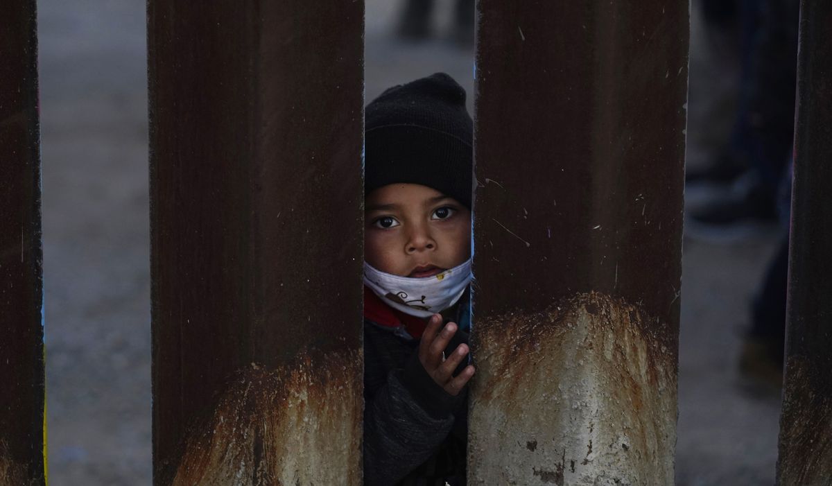 A young boy, part of several asylum seeking families participating in a Las Posadas event at the U.S.-Mexico border wall, peers into the U.S. from Agua Prieta, Mexico Tuesday, Dec. 15, 2020, seen from Douglas, Ariz. People on each side of the border celebrate Las Posadas as they have done for decades, a centuries-old tradition practiced in Mexico re-enacts Mary and Joseph