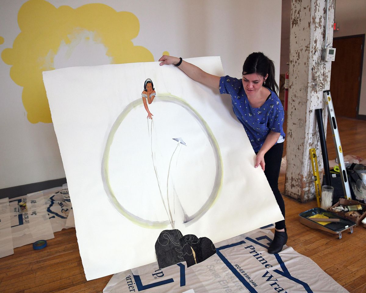 Jackie Caro, operations director for Terrain, holds artwork by Heather Hart that is being hung in Terrain