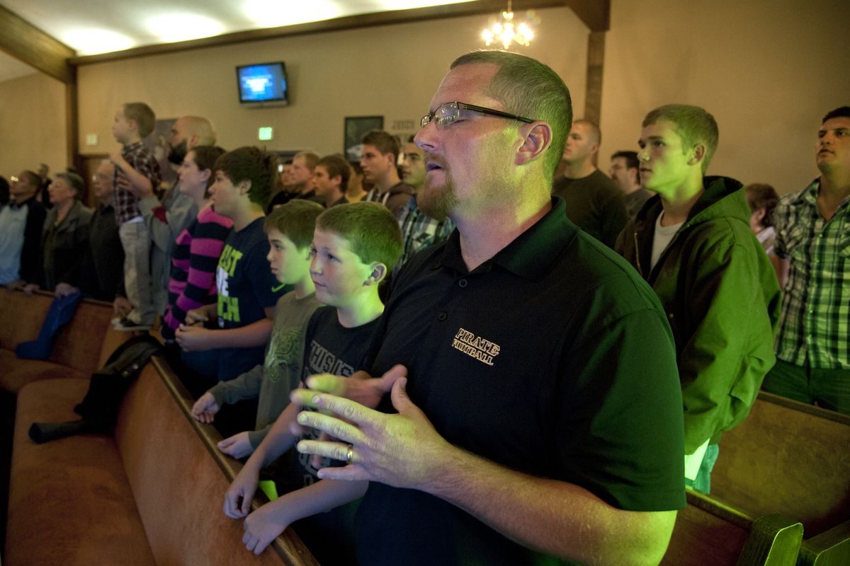 Rogers High head coach Matt Miethe, his children, and Rogers players and coaches gather for a Sunday prayer service at the Colbert Chapel on Oct. 27.