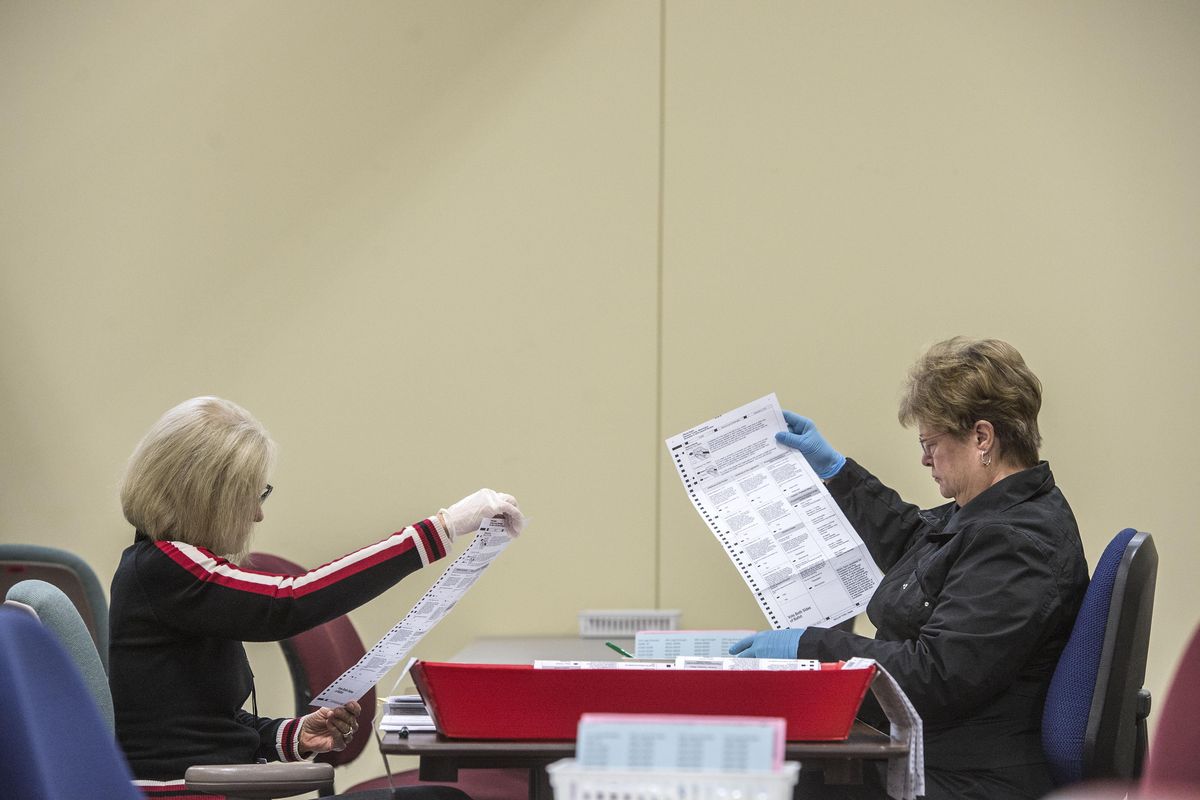 Spokane County election workers Pat Curiale, left, and Sue Harvey inspect ballots for machine readability, Oct. 25, 2016, at the election center. (Dan Pelle / The Spokesman-Review)