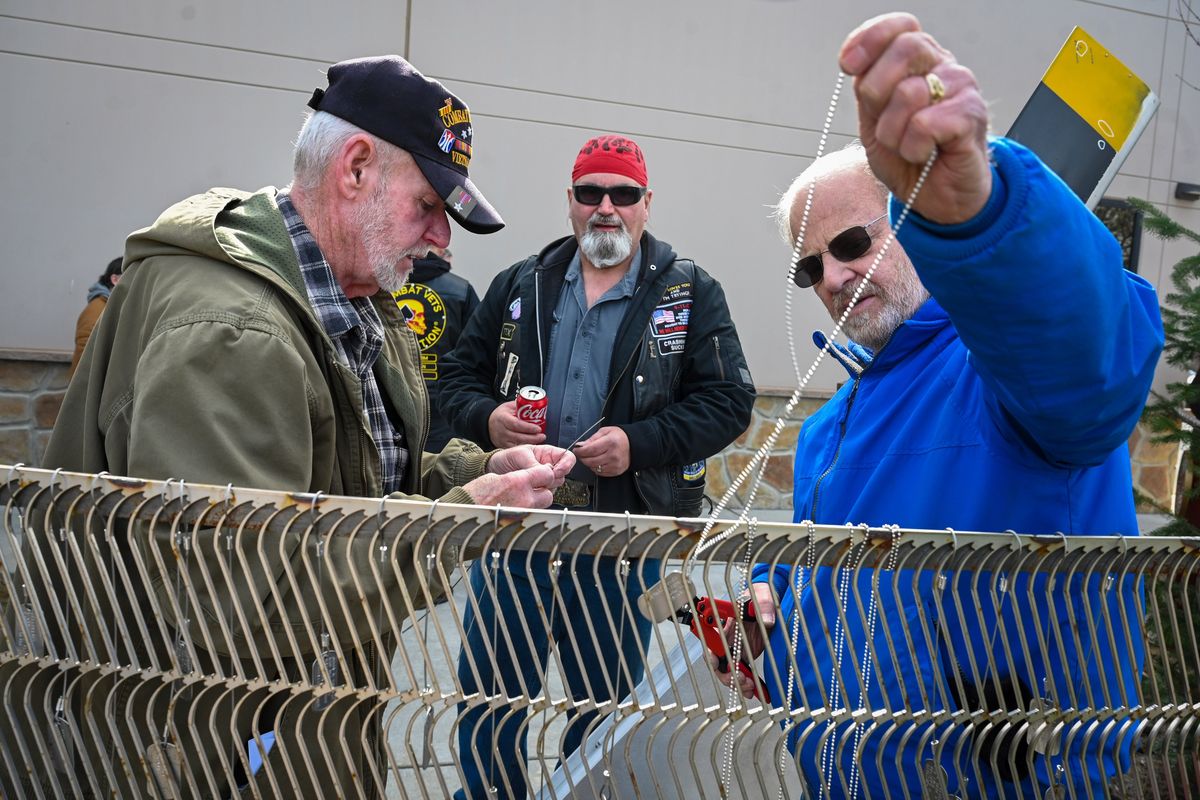 Mac Gillivary, U.S. Army veteran, left, and Navy veteran Dave Strand, right, hang the dog tags on the Vietnam War Memorial honoring the grandfather and father of Army veteran Tex Swendig, center, during the Spokane Vet Center’s Welcome Home Vietnam Veterans event.  (DAN PELLE/THE SPOKESMAN-REVIEW)