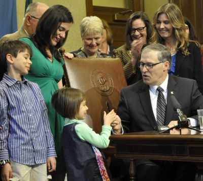 Gov. Jay Inslee hands the official signing pen to 5-year-old Zoe Adler, of Seattle, while her brother, Jake, 9, and a crowd of legislators and other supporters look on after HB 2315, which sets up new programs to help prevent suicides, was signed into law. The children’s father, Matt Adler, committed suicide three years ago. (Jim Camden)