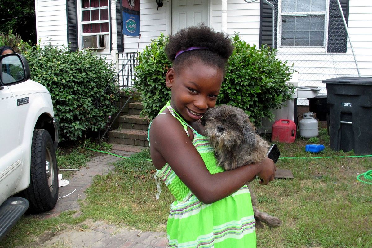 Regina Harrell, 9, holds her dog Roscoe outside her home in North Augusta, S.C. While she played alone at a local park, her mother was arrested for neglect. (Associated Press)