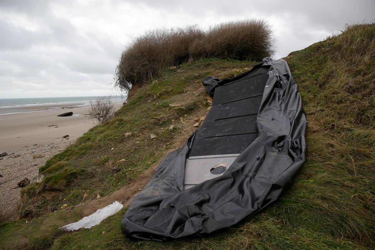 A damaged inflatable small boat is pictured on the shore in Wimereux, northern France, Thursday, Nov. 25, 2021 in Calais, northern France. Children and pregnant women were among at least 27 migrants who died when their small boat sank in an attempted crossing of the English Channel, a French government official said Thursday. French Interior Minister Gerald Darmanin also announced the arrest of a fifth suspected smuggler thought to have been involved in what was the deadliest migration tragedy to date on the dangerous sea lane.  (Michel Spingler)