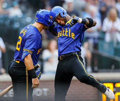 Victor Robles, right, is welcomed home by Cal Raleigh following his lead-off home run against Philadelphia on Aug. 2 in Seattle.  (Dean Rutz/Seattle Times)