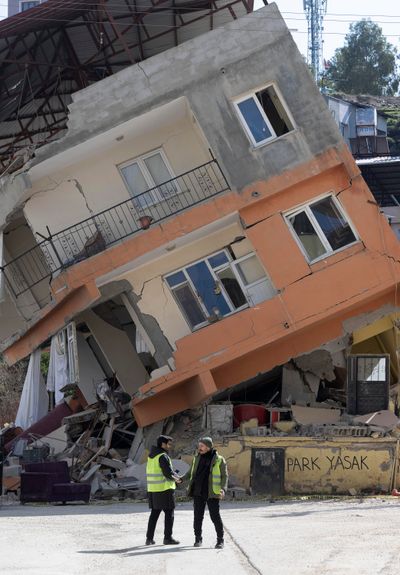Two men walk past a destroyed house on Tuesday in Kirikhan, Turkey.  (Boris Roessler/dpaBORIS ROESSLER/TRIBUNE NEWS SERVICE)