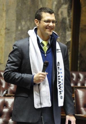 OLYMPIA -- Senate Majority Floor Leader Joe Fain, R-Auburn, sports a Seattle Seahawks hood and scarf as he moves the Senate through the pro forma session Friday. A dress code that usually requires business attire on the Senate floor was relaxed to allow Seahawks jerseys and other paraphernalia or blue and green clothing. (Jim Camden)