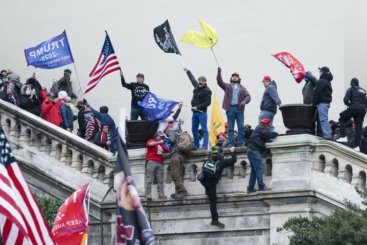 In this Jan. 6, 2021 photo, rioters wave flags on the West Front of the U.S. Capitol in Washington. Two Seattle police officers who were in Washington, D.C., during the Jan. 6 insurrection were illegally trespassing on Capitol grounds while rioters stormed the building, but lied about their actions, a police watchdog said in a report released Thursday, July 8, 2021. (Jose Luis Magana)