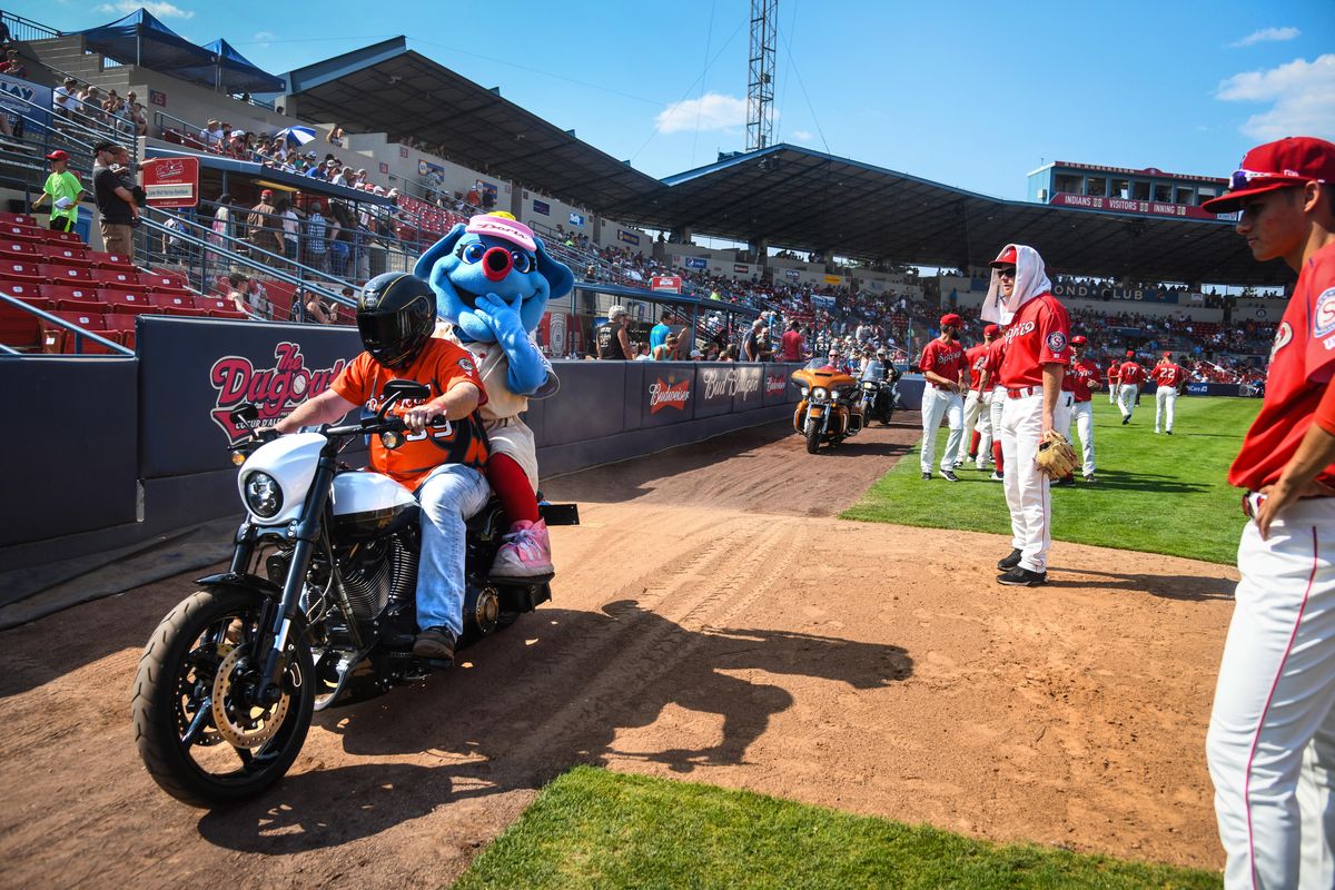 Spokane Indians mascot, Doris the Spokanasaurus, gets a ride from Ryan Hendricks aboard his Harley-Davidson CVO Pro Street Breakout motorcycle as some 100 cycles participate in the Ride the Bases at Avista Stadium before the Indians played the Hillsboro Hops, Sunday, July 29, 2018. Motorcyclists raised money for the Rypien Foundation. (Dan Pelle / The Spokesman-Review)