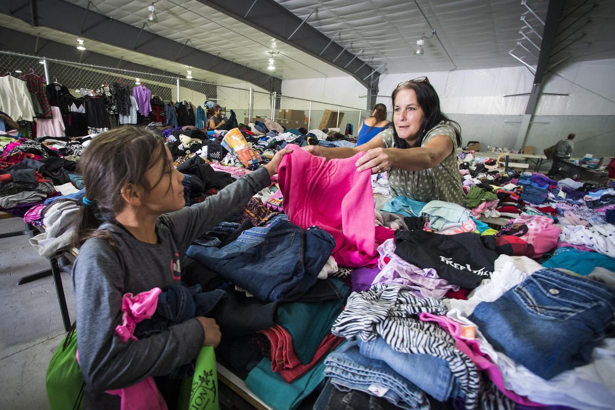 Angela Andrew hands her grand daughter Cienna Abrahamsom, 7, a shirt she might like inside a Wellpinit School warehouse full of donated clothing,Thursday, Aug. 25, 2016. Shipments have been arriving every hour from other tribes and surrounding communities. They include everything from bottled water, clothing, hygiene products and furniture. Local leaders say the donated items have helped people impacted by the fire get back on their feet. (Colin Mulvany colinm@spokesman.com / SR)