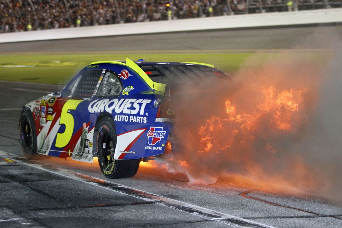 Mark Martin drives down pit road with his car engulfed in flames after a crash.  (Associated Press)