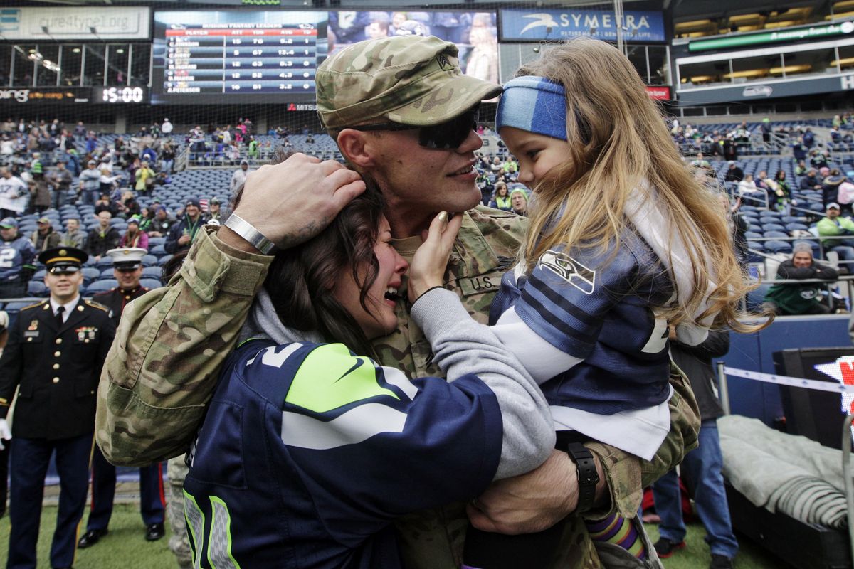 United States Army Sgt. Zach Ames, center, who has been on a one-year deployment to Afghanistan, surprises his wife, Bri Ames, left, and their daughter Emersyn, right, with a reunion prior to an NFL football game between the New York Jets and the Seattle Seahawks on Veterans Day, Sunday, Nov. 11, 2012, in Seattle. (Elaine Thompson / Associated Press)