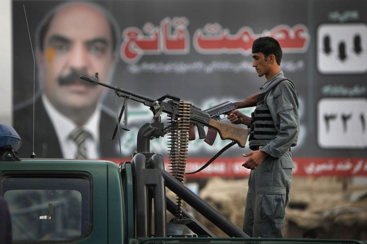 An Afghan policeman provides a very visible show of security in front of an election campaign billboard in Kabul, Afghanistan, on Friday.  (Associated Press)
