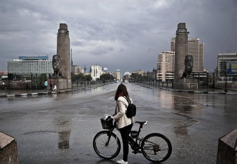 A 27-year old Egyptian artist stops with her bicycle in front of the Kasr Al Nile bridge that leads to Tahrir Square, after making her way back from the square, during the fifth anniversary anniversary of the 2011 uprising, in Cairo, Egypt.  (AP Photo/Nariman El-Mofty)