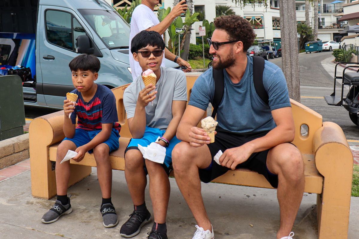 From left, Jacob Tagaban, 12, and Joseph Tagaban, 15, have an ice cream cone with Golden State Warriors star and four-time NBA champion Klay Thompson on July 15 on a beach in San Clemente, California.  (Madeline Kenney/Bay Area News Group/TNS)