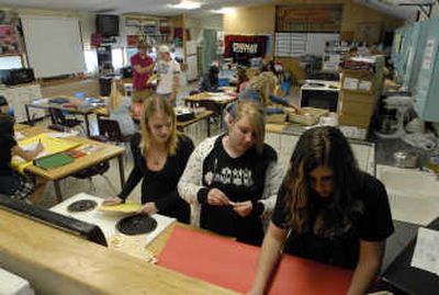 
Freeman  freshmen Carlie Dickson, Morgan Verggran and Mychelle  Merendino make posters using a stove and a cutting board in the family consumer sciences room last week. 
 (J. Bart Rayniak / The Spokesman-Review)