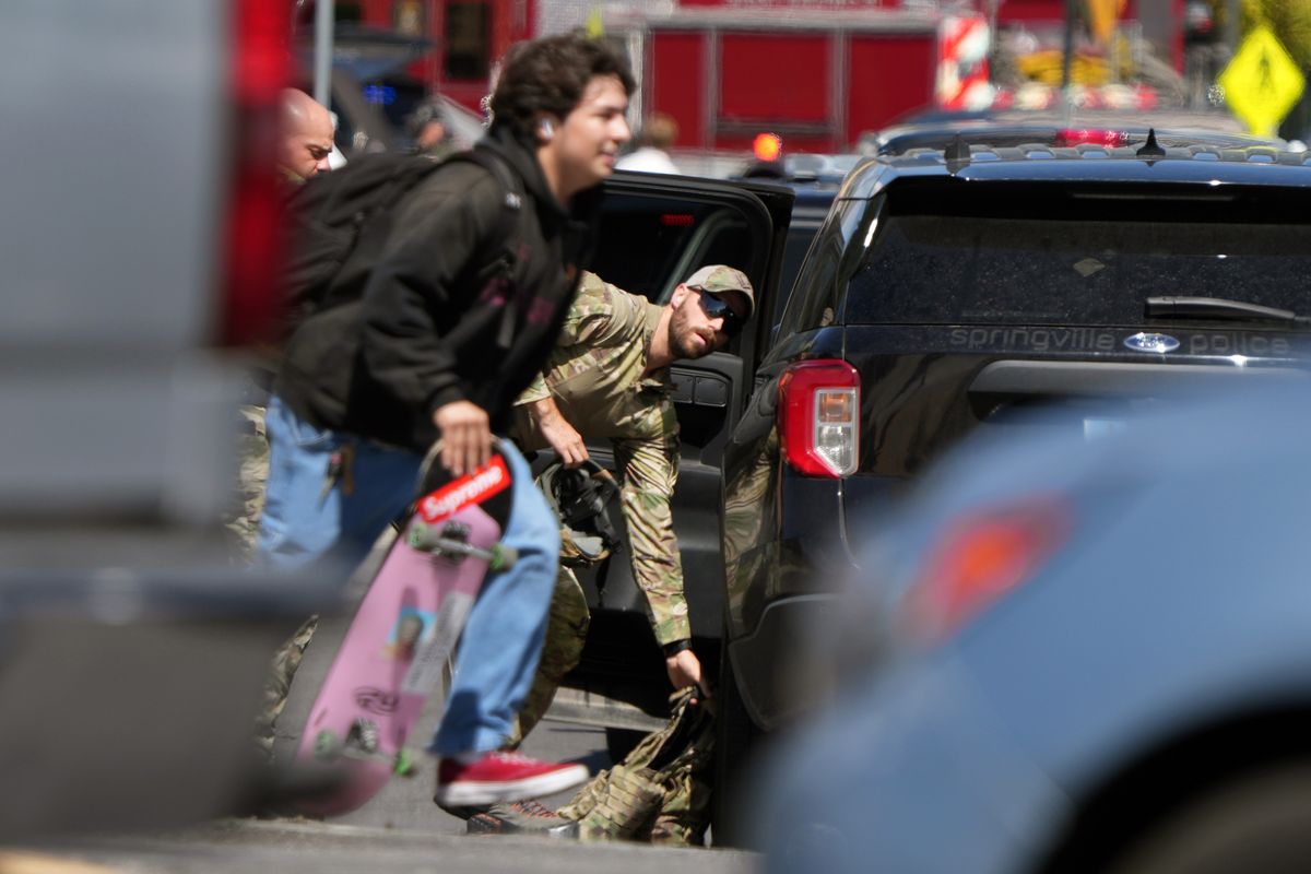 A person with a skateboard evacuates as law enforcement responds to the scene where political activist Charlie Kirk was shot during an event at Utah Valley University on Wednesday, Sept. 10, 2025, in Orem, Utah. Kirk, founder of Turning Point USA, was speaking at his "American Comeback Tour" when he was shot in the neck and killed. (George Frey/Getty Images/TNS)  (George Frey/Getty Images North America/TNS)