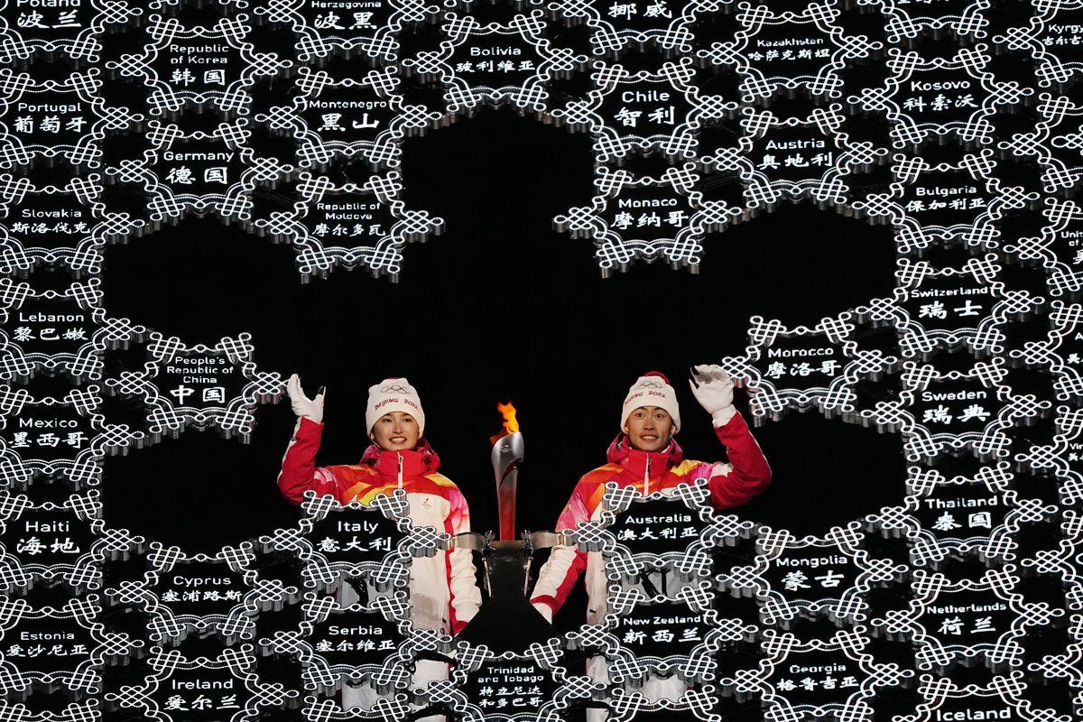 China's athletes Dinigeer Yilamujian and Zhao Jiawen wave before lighting the cauldron during the opening ceremony of the 2022 Winter Olympics, Friday, Feb. 4, 2022, in Beijing.  (David J. Phillip)