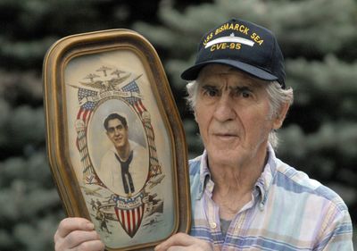Ernie Peluso, of Post Falls, holds a colorized photograph of himself taken just before he got out of the Navy in 1945. . The Spoksman-Review (J. BART RAYNIAK The Spoksman-Review / The Spokesman-Review)