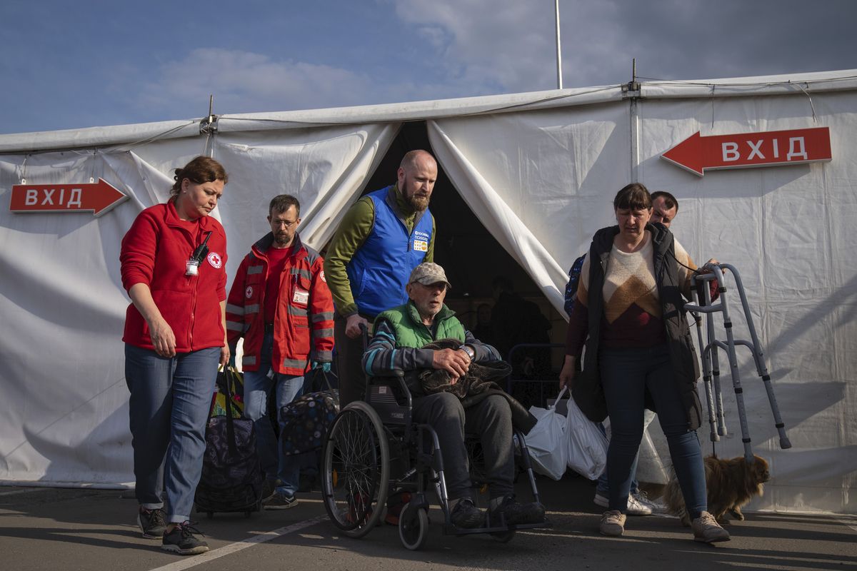 FILE - Volunteers assist a man after his arrival from the Ukrainian city of Mariupol at a center for displaced people in Zaporizhzhia, Ukraine, May 3, 2022. With the evacuation of some civilians from a sprawling steel mill besieged by Russian forces, attention is turning to the fate of hundreds of Ukrainian troops still inside after weeks in the warren of underground tunnels and bunkers.  (Evgeniy Maloletka)