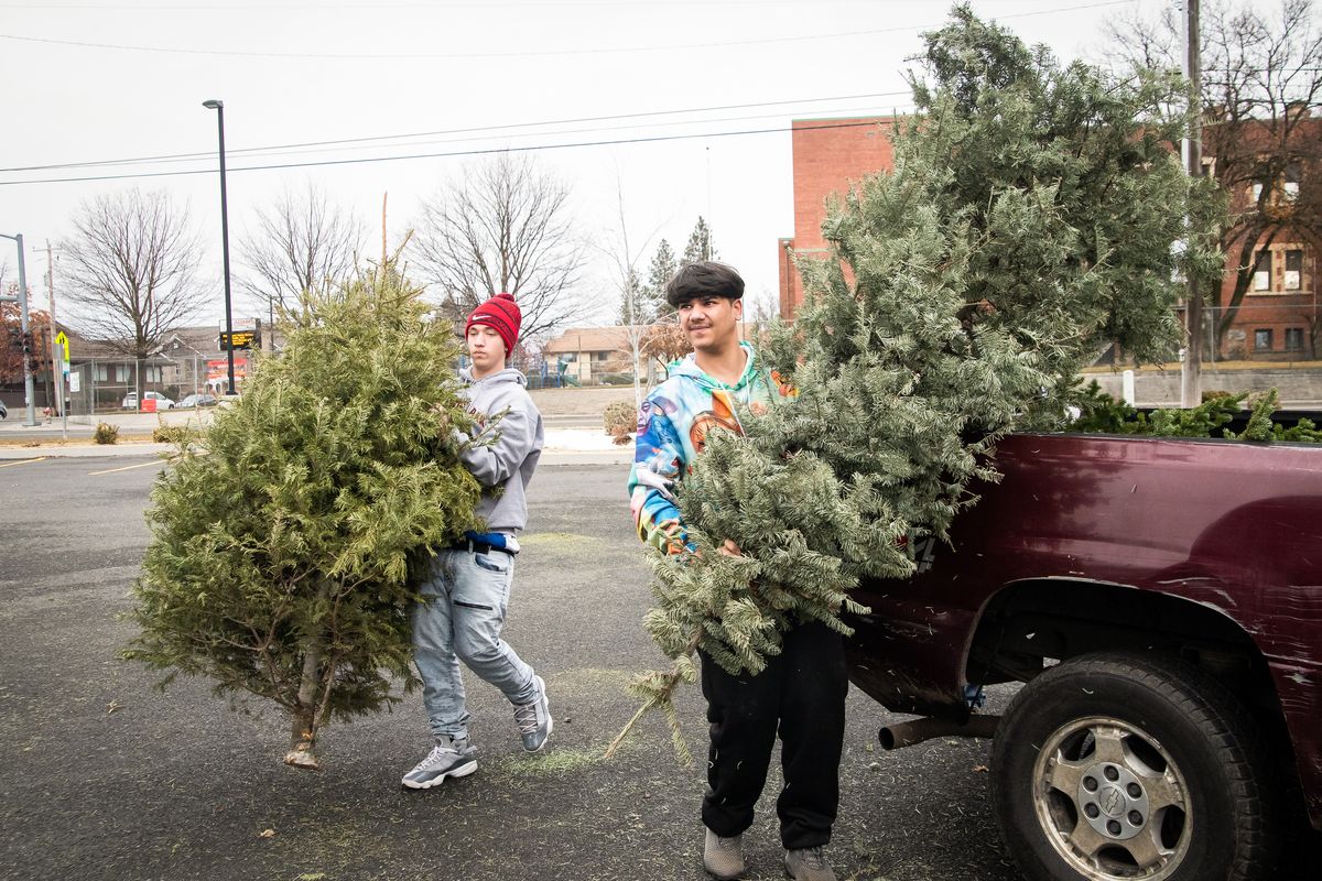 Sophomores Christian Proctor, left, and Raynehil Karunaratne carry Christmas trees to a large bin during the last day of Ferris High School’s Christmas tree recycling fundraiser on Sunday. Proceeds raised from the event will be used for the “senior all-nighter,” an annual drug-free year-end celebration for the senior class. Due to the COVID-19 pandemic, the board is unsure whether an in-person gathering will be possible but are considering alternatives to celebrate the class of 2021 with. The ongoing pandemic also reduced the amount of volunteers that usually run the fundraiser, but resulted in more than half of donors contributing more than the $5 suggested donation in an effort to give seniors more to look forward to.  (Libby Kamrowski/ THE SPOKESMAN-REVIEW)