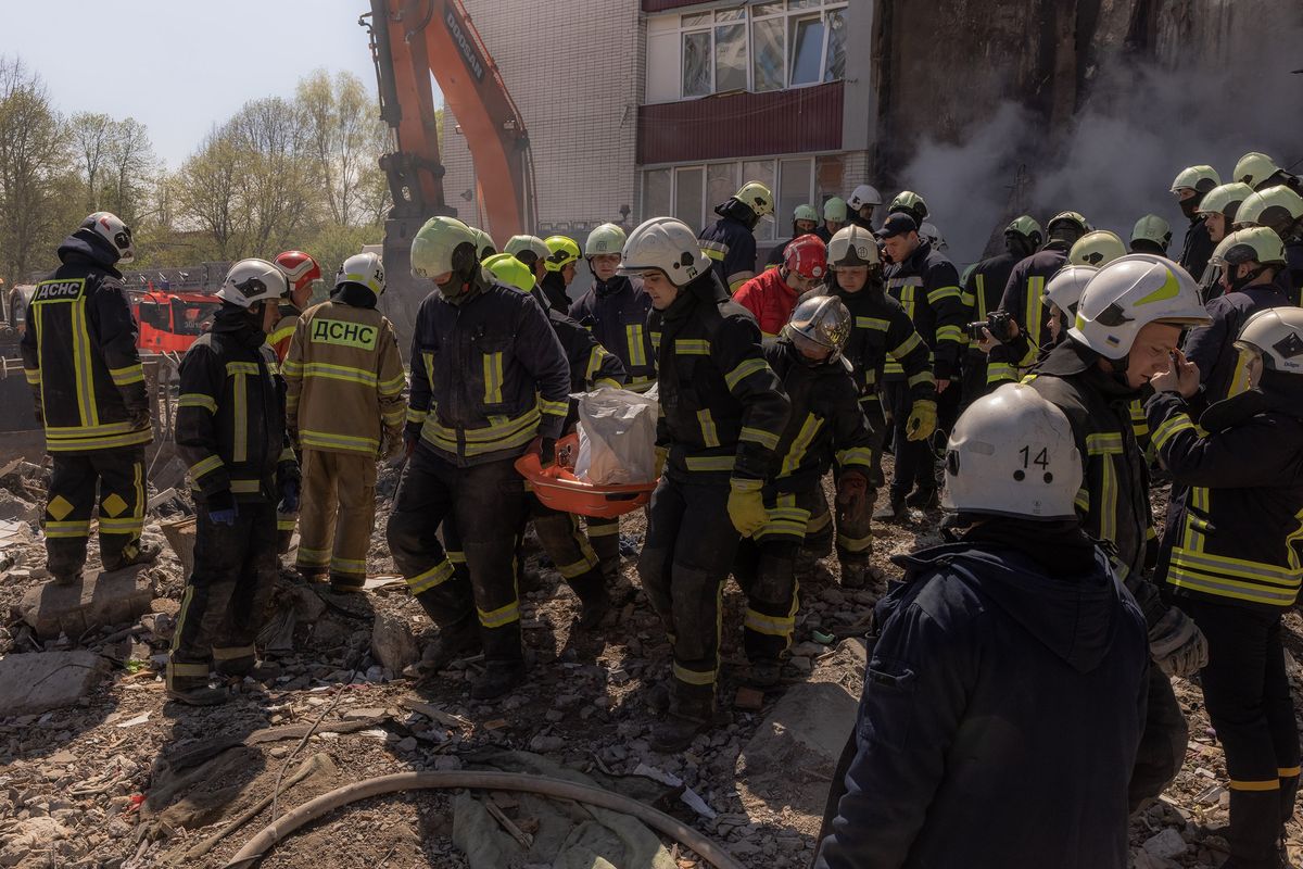 Firefighters carry a body of a victim from the destroyed residential building following the Russian attack, on April 28, 2023, in Uman, Ukraine.    (Roman Pilipey/Getty Images Europe/TNS)