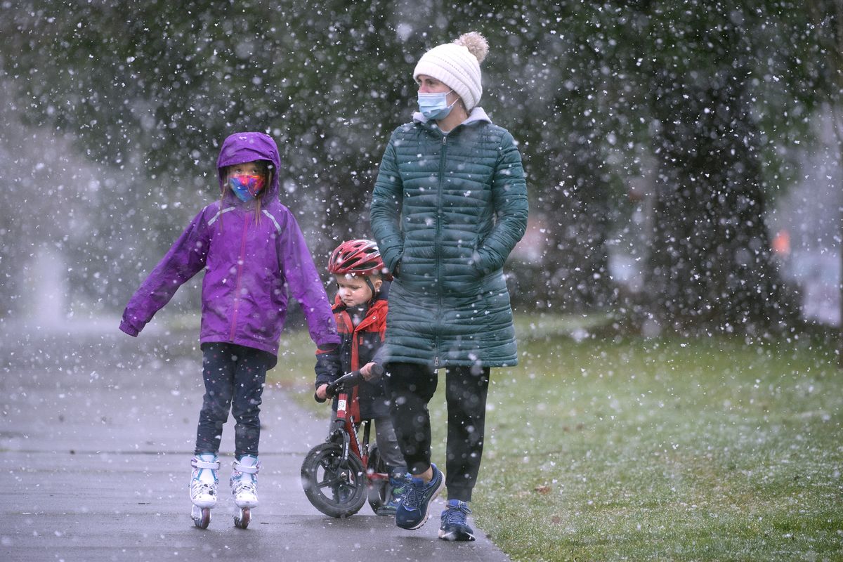 Jackie Johnson walks through the falling snow with her daughter Lindley, 7, and son William, 3, after dropping off her other son John for kindergarten, in DuPont, Wash., Thursday, Feb. 11, 2021.  (Tony Overman)
