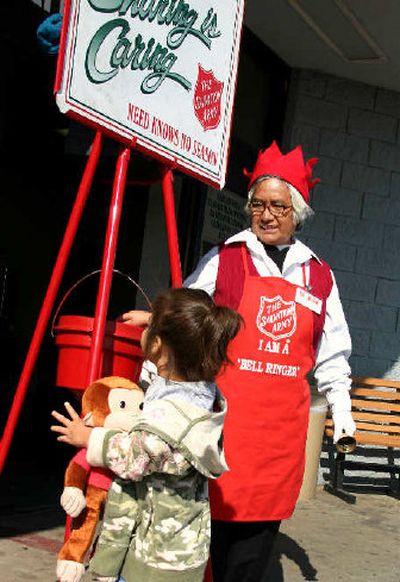 
Edita Lara, bell-ringer for the Salvation Army, watches as Anmaree Reyes, 3, drops coins into the red donation bucket at Wal-Mart.
 (Associated Press / The Spokesman-Review)