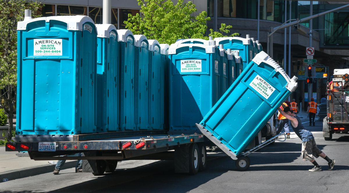 Michael Hensley, of American On-Site Services, loads one of 300 port-a-potties onto a trailer on Riverside Avenue after the race. (Dan Pelle / The Spokesman-Review)