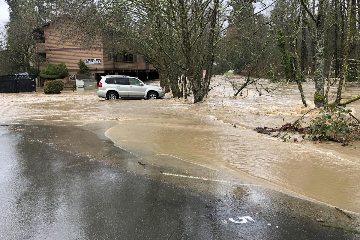 An apartment building is flooded by overflowing Issaquah Creek, right, in Issaquah, Wash., as heavy rains pound the area Thursday, Feb. 6, 2020. Rain storms are triggering flood warnings on rivers across western Washington state. (Martha Bellisle / Associated Press)