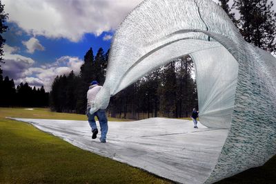 Don Nelson, left, and Bob Morgan, right rear, hold on as wind catches the cover they’re pulling off the 12th green Monday at Indian Canyon Golf Course in Spokane. The city plans to open Esmeralda, Downriver and Qualchan golf courses Thursday.   (CHRISTOPHER ANDERSON / The Spokesman-Review)