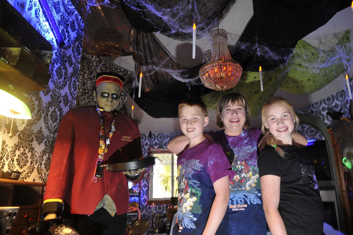 Kristie Gaffney and her younger children, twins Keaton, left, and Kyra, right, 12, stand in their living room Wednesday. Gaffney has turned her home into a not-too-scary haunted house with decorated walls, animated figures, statues and pictures. They live in Greenacres. (Jesse Tinsley)