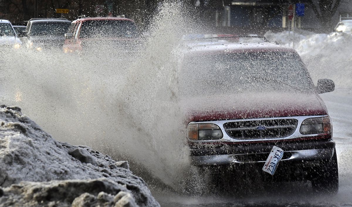 Vehicles make waves in a giant puddle Wednesday at North Magnolia Street and East Mission Avenue  in Spokane.  (Dan Pelle / The Spokesman-Review)