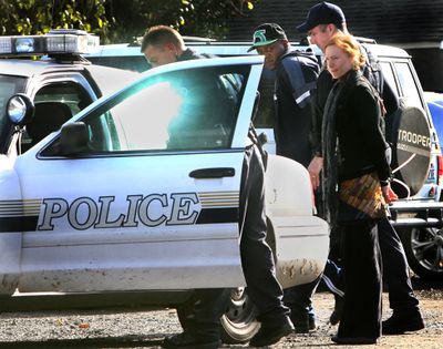 Olympia police transport two people taken into custody after the Thurston County Narcotics Task Force served search warrants at Olympia Patient Resource Center. (Associated Press)