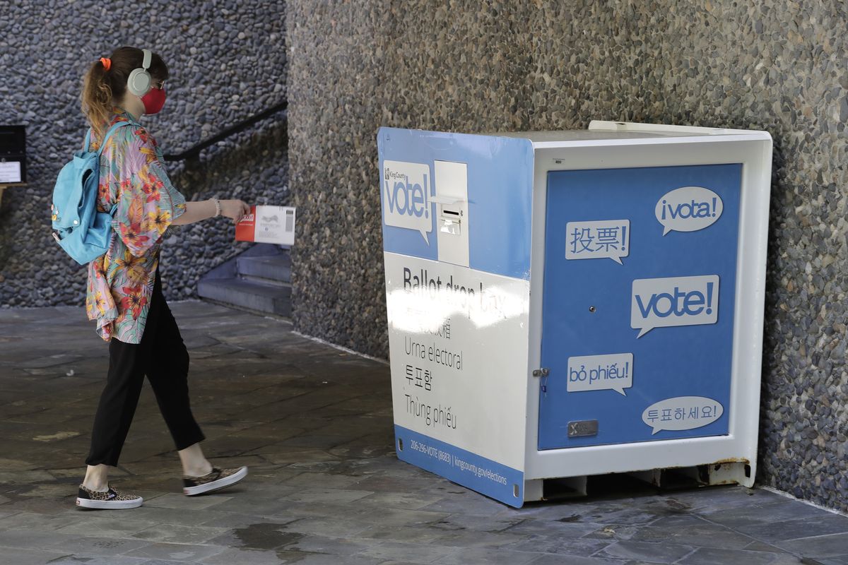 A person drops off a ballot for Washington state’s primary election, Tuesday, Aug. 4, 2020, at a collection box at the King County Administration Building in Seattle. Voters in the state have the option of voting by mail, depositing ballots in boxes, or seeking help in person for a missing ballot or other issues.  (Ted S. Warren)