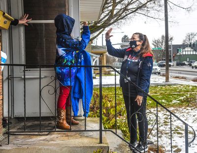 Judy Reavis, a 5th-grade teacher at Logan Elementary in a low-income section of northeast Spokane, makes her 100th home visit and gives a distance-high five to her student Bella Quantrille-Hinkel, Friday, Jan. 29, 2021, in Spokane. Reavis is helping her students stay connected during the pandemic.  (Dan Pelle/THESPOKESMAN-REVIEW)