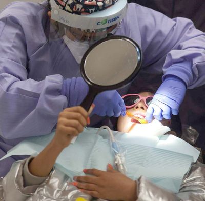 Clara Solorzano, a second year dental hygiene student at Tarrant Community College, cleans a 10-year-old’s teeth in 2021. An associate professor at UNT Health Fort Worth is researching how dental health providers can talk with patients about preventing HPV-related cancers.  (Amanda McCoy)
