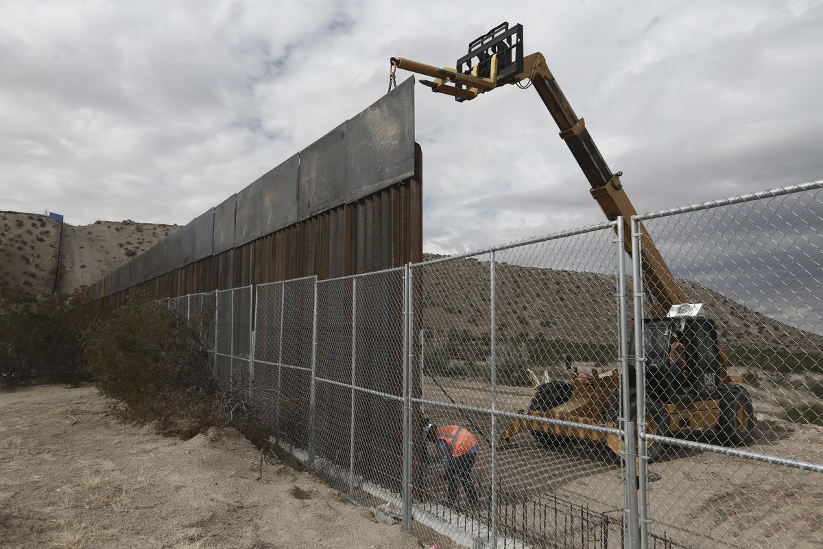 In this Nov. 10, 2016, file photo, workers raise a taller fence along the Mexico-US border between the towns of Anapra, Mexico and Sunland Park, New Mexico, where for almost two decades a Mass has been celebrated on Day of the Dead to remember migrants who have died trying to cross the fence. President Donald Trump wants a wall along the nearly 2,000-mile border. (Christian Torres / Associated Press file)