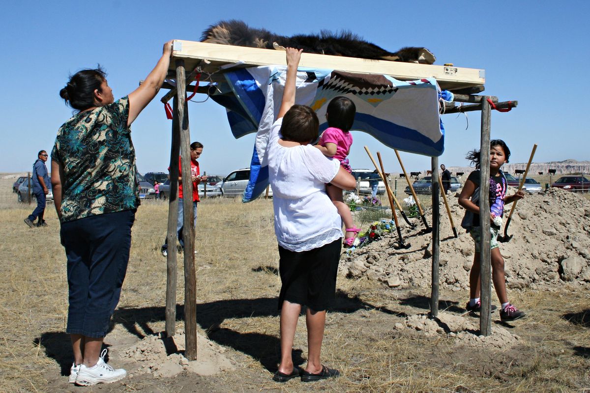 Marlis Afraid of Hawk, center left, touches the buffalo robe wrapped around the remains of her ancestor, Albert Afraid of Hawk, Sunday, Sept. 9, 2012, in Manderson, S.D. Albert Afraid of Hawk, a member of the Oglala Sioux Tribe, died 112 years ago while performing with Buffalo Bill