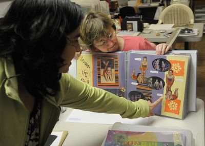 Crystal Ray, right, shows off one of her scrapbooks to Adrianna Gmeiner during a session at Ray’s home on April 24 in south Spokane. (Dan Pelle / The Spokesman-Review)