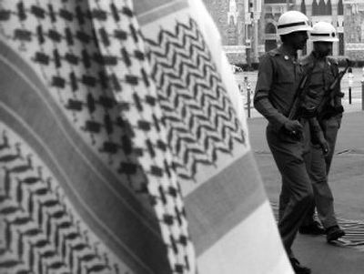 
 Police stand guard Feb. 7 outside the Grand Mosque in Mecca, Saudi Arabia, as an unidentified man wearing a red-and-white headscarf looks on. 
 (Associated Press / The Spokesman-Review)